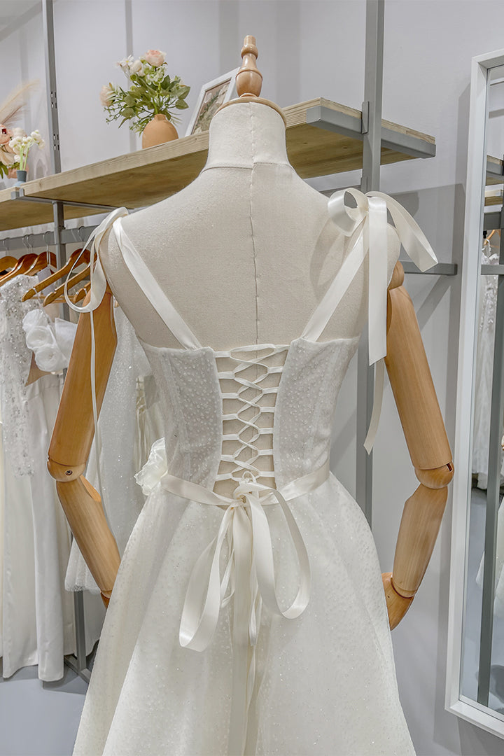 Булчинска рокля Clarissa LIZA KAIN София. Бяла официална рокля. Полупрозрачен корсет с презрамки с панделки и връзки на гърба. Колан с панделка. Пола със средна дължина.