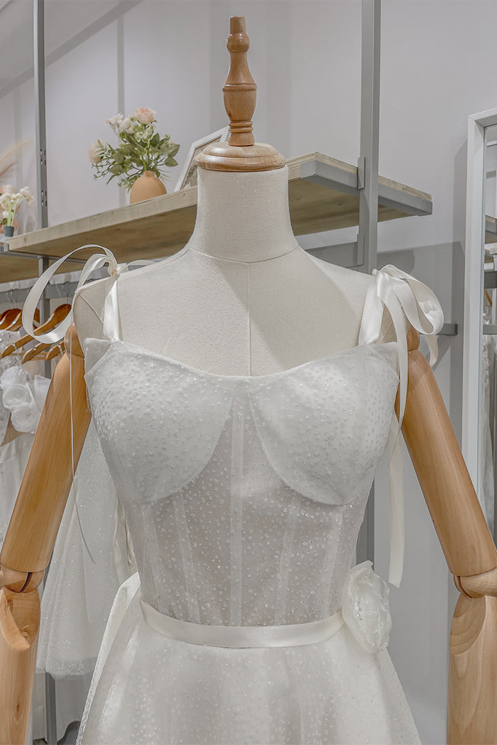 Булчинска рокля Clarissa LIZA KAIN София. Бяла официална рокля със средна дължина. Полупрозрачен корсет с чашки и презрамки с панделки. Колан с апликация от цвете. Разкроена пола от тюл.