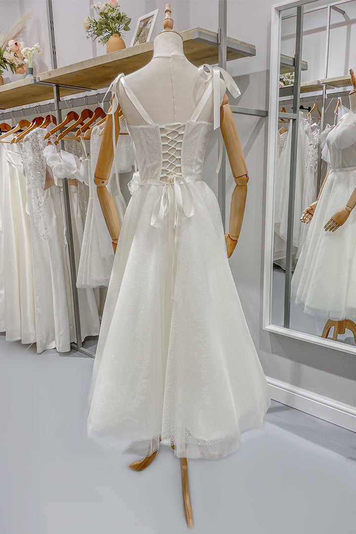 Булчинска рокля Clarissa LIZA KAIN София. Бяла официална рокля. Полупрозрачен корсет с презрамки с панделки и връзки на гърба. Колан с панделка. Разкроена тюлена пола със средна дължина.