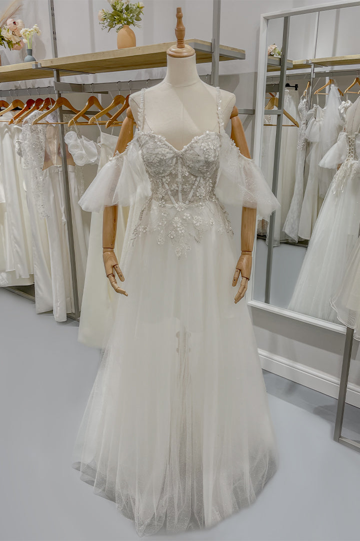 Дълга булчинска рокля Felicity LIZA KAIN София. Бяла официална тюлена рокля. Деколте с чашки и презрамки с флорална дантела. Дълга прозрачна тюлена пола с подплата. Паднали ръкави.