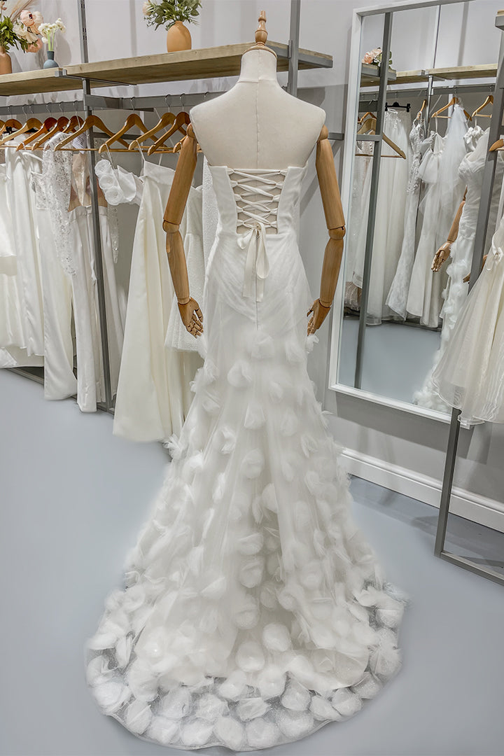 Дълга булчинска рокля Floressa LIZA KAIN София. Бяла официална рокля с паднала талия и корсет с драперия и връзки. Силует русалка с апликации от тюлени цветя и висока цепка. Дълъг прозрачен шлейф с апликации.