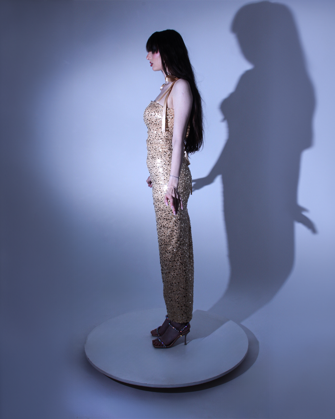 Дълга окля Collete LIZA KAIN София. Официална рокля от златист сатен, покрит с фина златиста дантела от пайети и мъниста. Корсет с равно деколте и презрамки тип панделка. Връзки на гърба. Права пола до глезена с шлиц.