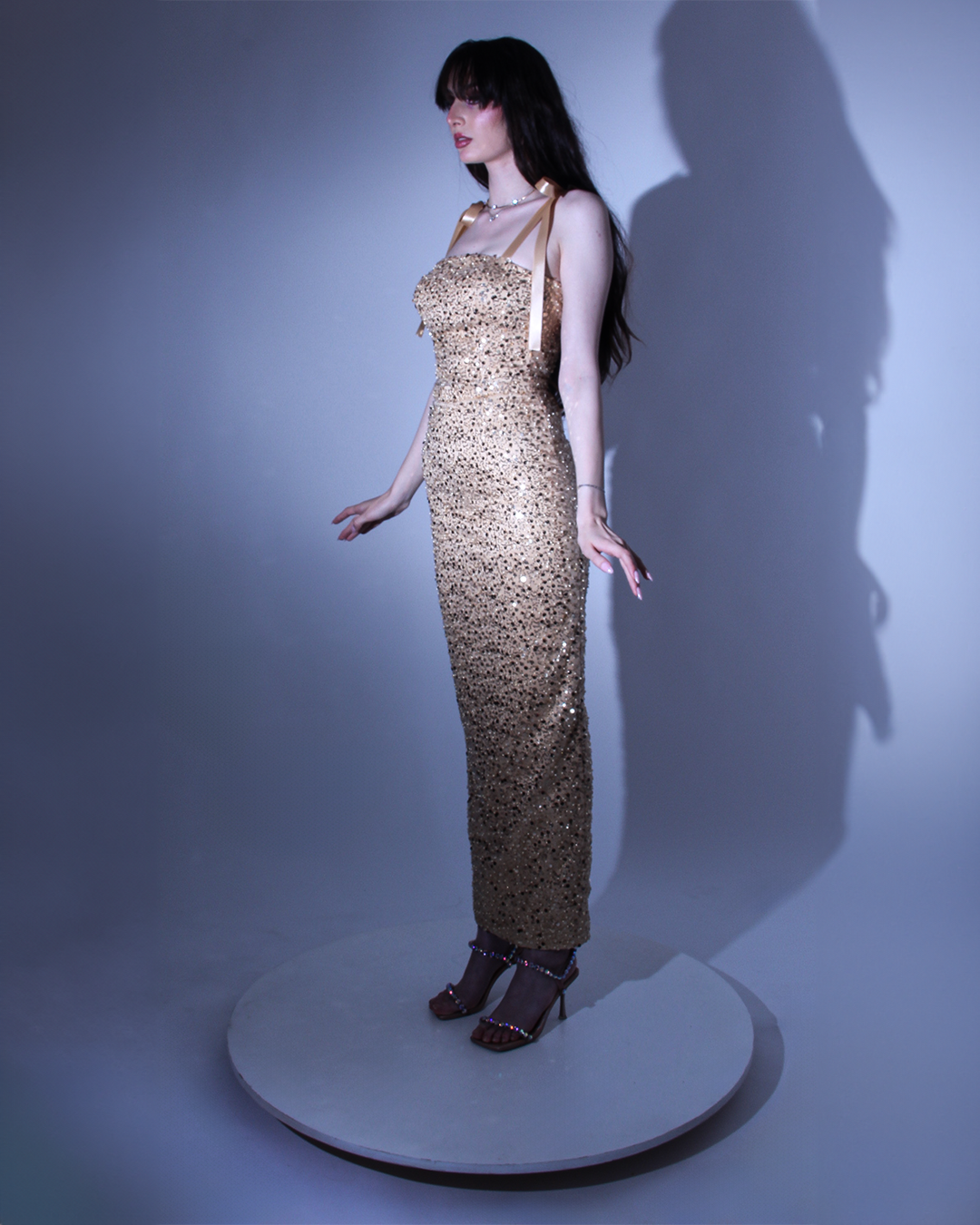 Рокля Collete LIZA KAIN София. Официална рокля от златист сатен, покрит с фина златиста дантела от пайети и мъниста. Корсет с равно деколте и презрамки тип панделка. Връзки тип панделка на гърба. Права пола до глезена с шлиц отзад.