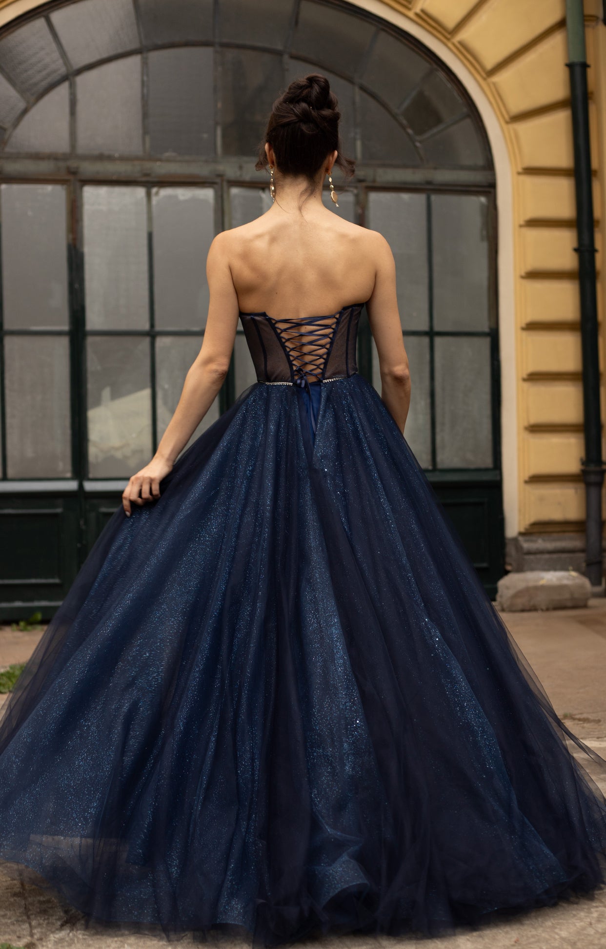 Официална дълга абитуриентска рокля Etara LIZA KAIN София. Обемна тъмносиня тюлена рокля. Прозрачен гръб с връзки. Блестяща обемна тюлена пола с висока цепка.