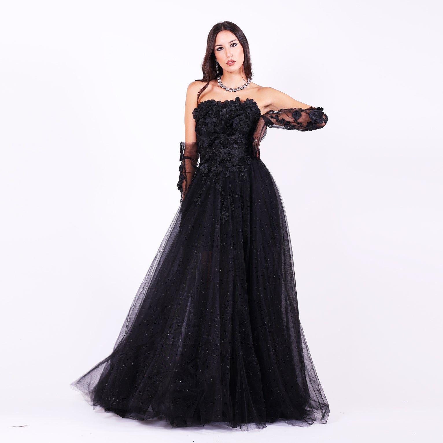 Дълга абитуриентска рокля Gloriosa LIZA KAIN София. Официална рокля от черен тюл с разкроена кройка. Корсет с равно деколте, покрит с памучна дантела на цветя. Обемна тюлена пола с подплата. Тюлени ръкавици с цветя.