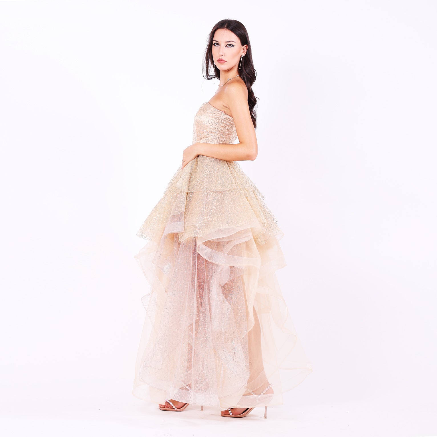 Дълга абитуриентска рокля Nerium LIZA KAIN София. Официална рокля от бежов сатен и тюл. Корсет с равно деколте с мрежа, покрит със златист блестящ тюл. Бухнала тюлена пола с множество къси и дълги къдрици от различни тюлове.