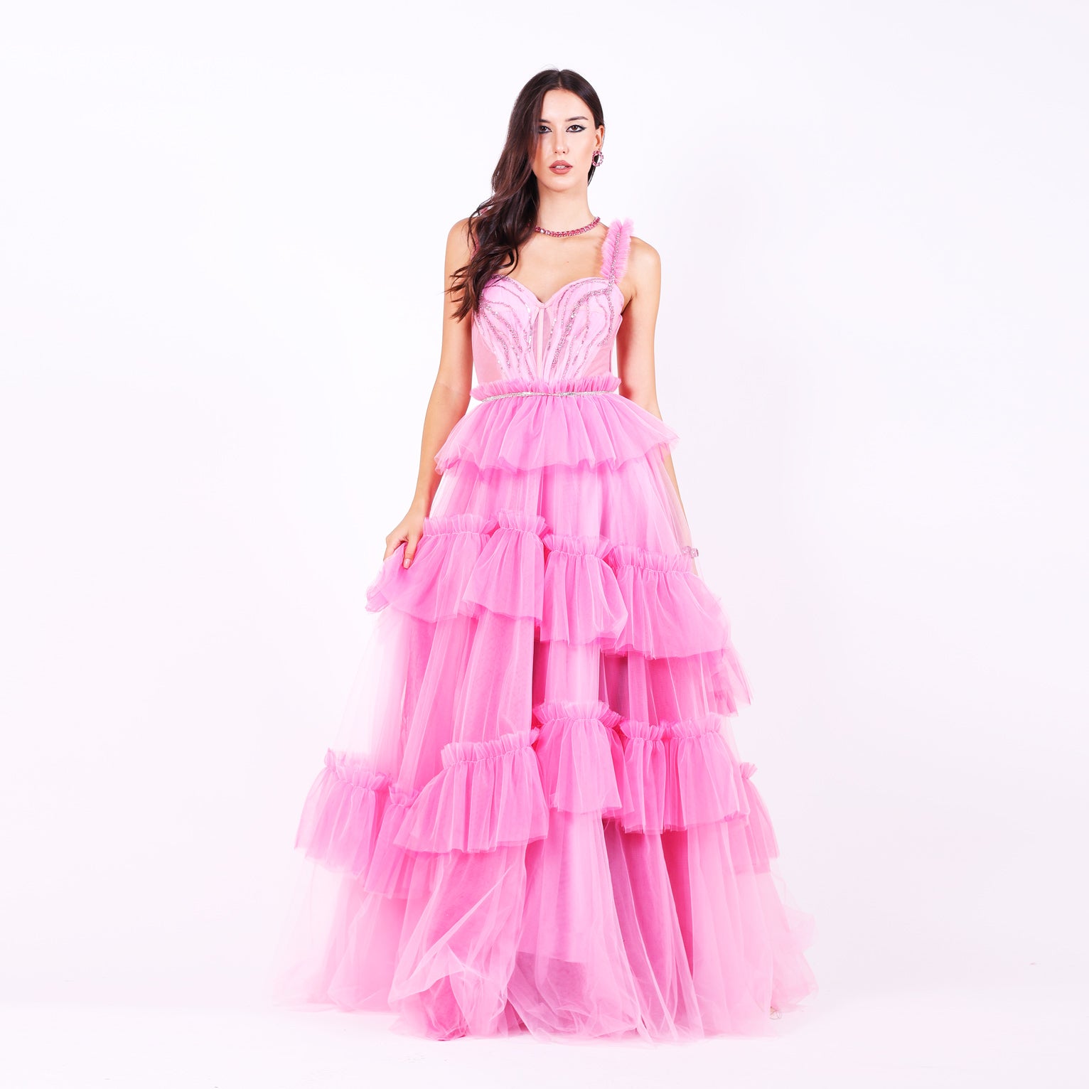 Дълга абитуриентска рокля Tiarella LIZA KAIN София. Официална рокля от розов тюл. Корсет със сърцевидно деколте с къдрави презрамки, покрит с розова дантела от мъниста. Бухнала тюлена пола с множество асиметрични волани.