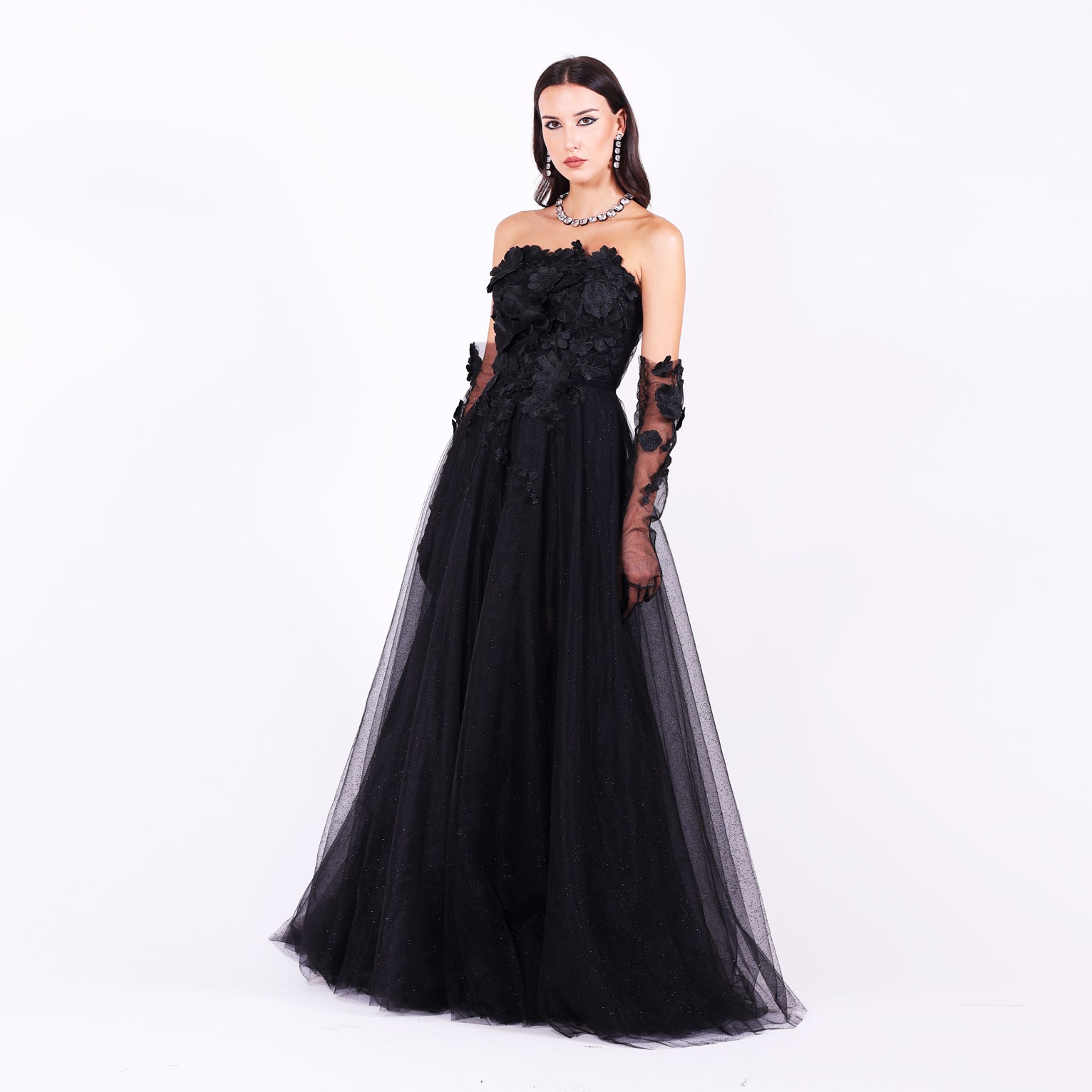 Дълга абитуриентска рокля Gloriosa LIZA KAIN София. Официална рокля от черен тюл и дантела. Корсет с равно деколте, покрит с флорална памучна дантела. Обемна тюлена пола. Тюлени ръкавици с пръсти.