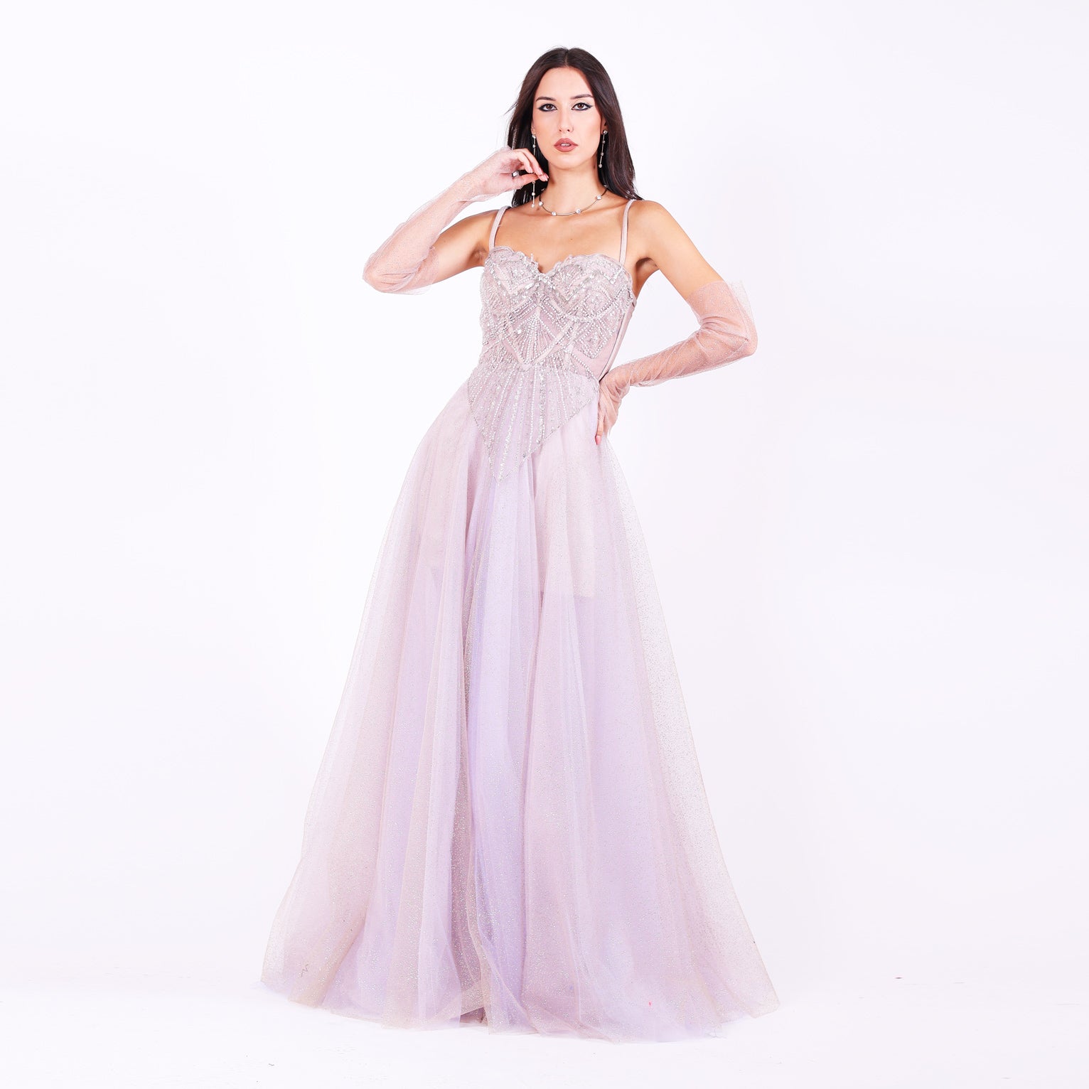 Дълга абитуриентска рокля Tilia LIZA KAIN София. Официална рокля от бледолилав тюл. Корсет с чашки с тънки презрамки и апликации от сребриста и бяла дантела от мъниста и перли. Издължен корсет на триъгълник от дантела. Обемна пола от множество слоеве тюл. Тюлени ръкавици.