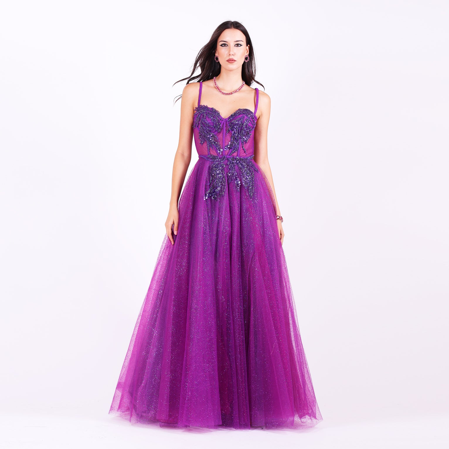 Дълга абитуриентска рокля Lavaterra LIZA KAIN София. Официална рокля от лилав тюл. Корсет със сърцевидно деколте с тънки презрамки и апликации от тъмно-лилава дантела от мъниста и камъчета. Бухнала пола от множество слоеве тюл с брокат. 