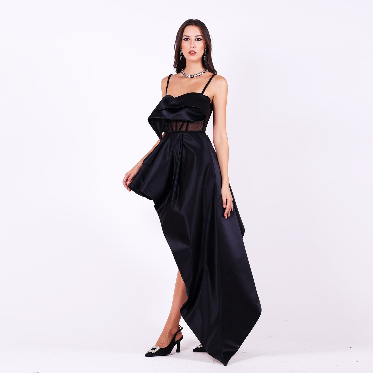 Дълга асиметрична абитуриентска рокля Stuartia LIZA KAIN София. Официална рокля от черен сатен. Корсет с полупрозрачна основа и сърцевидно деколте с презрамки. Падащи апликации от сатен. Разкроена асиметрична пола.