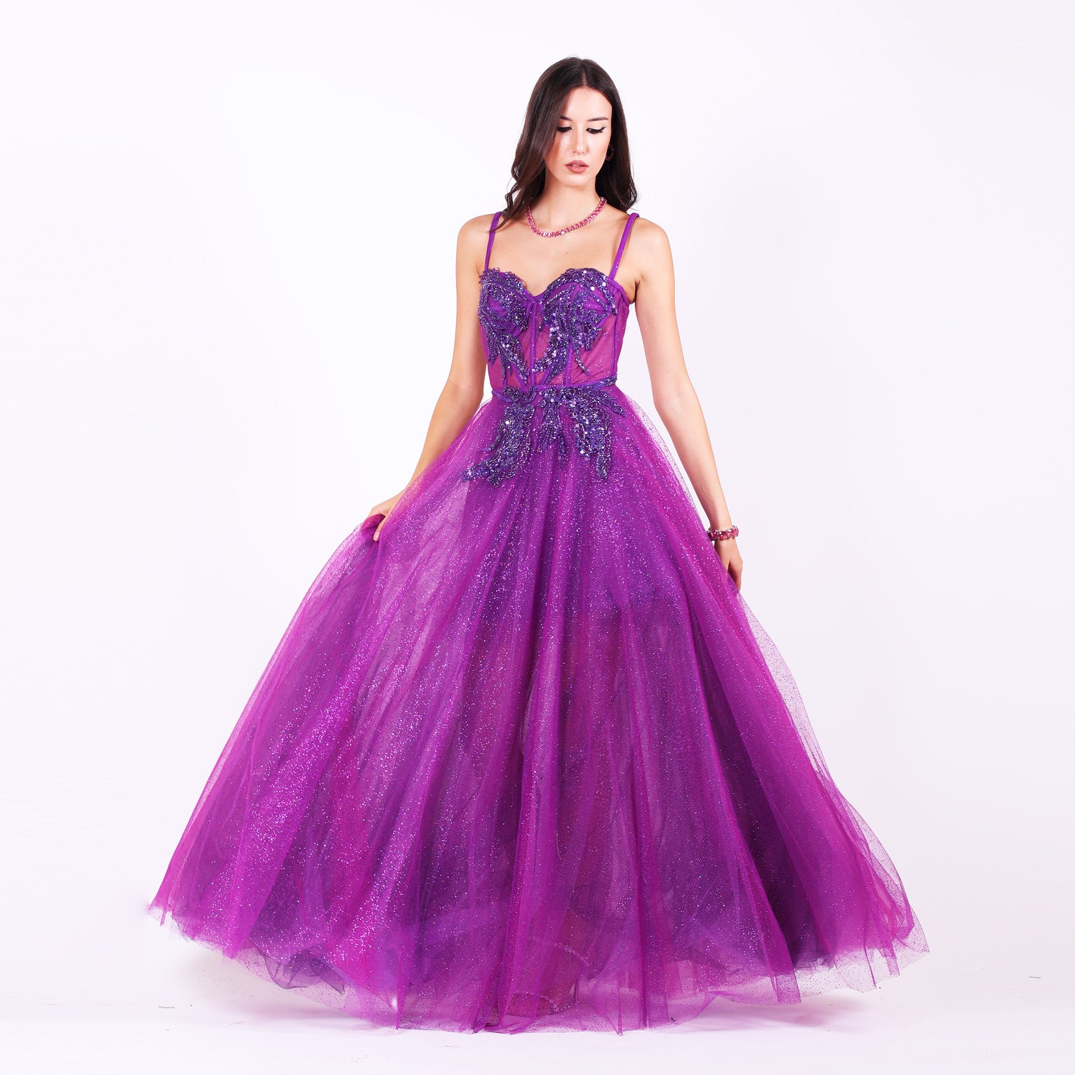 Дълга абитуриентска рокля Lavaterra LIZA KAIN София. Официална рокля от лилав тюл. Корсет със сърцевидно деколте с тънки презрамки и апликации от тъмно-лилава дантела от мъниста и камъчета. Бухнала пола от множество слоеве тюл с брокат. 