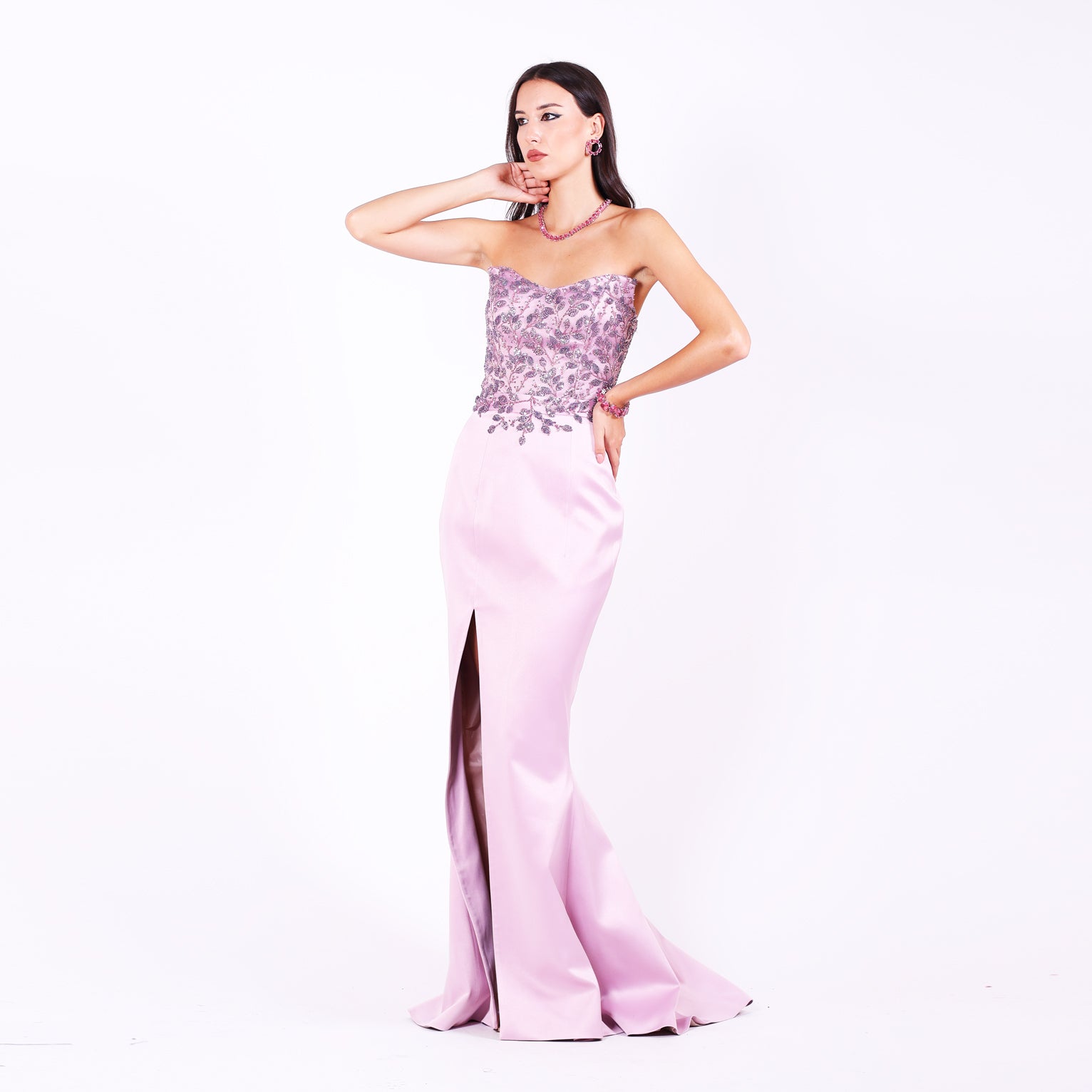 Дълга абитуриентска рокля Olea LIZA KAIN София от две части. Официална рокля от светлолилав сатен. Корсет със сърцевидно деколте без презрамки, покрит с лилава флорална дантела от мъниста. Пола тип русалка с цепка. 