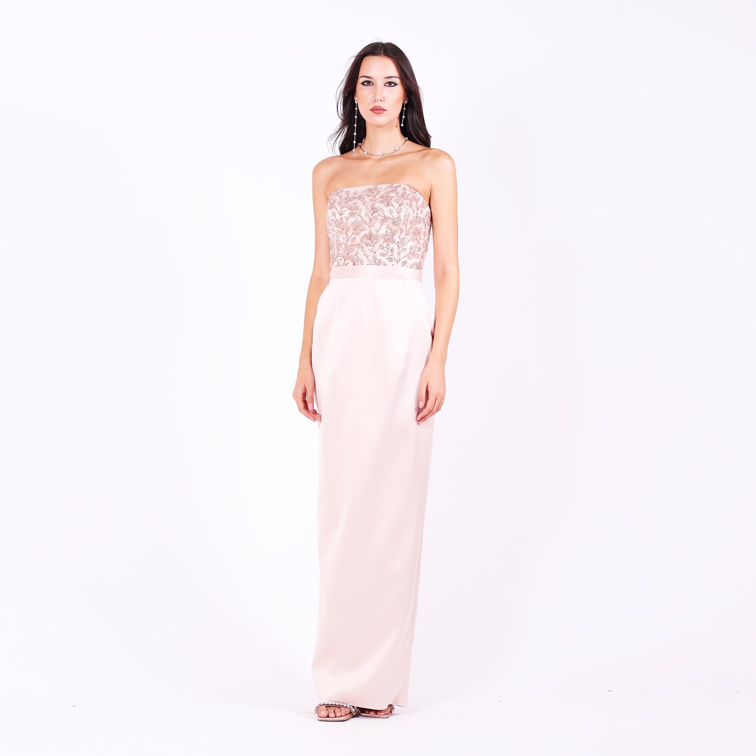 Дълга абитуриентска рокля Leea LIZA KAIN София. Официална рокля от светлорозов сатен. Корсет с равно деколте с апликации от розова флорална дантела от мъниста. Сатенен колан. Права сатенена пола по тялото.