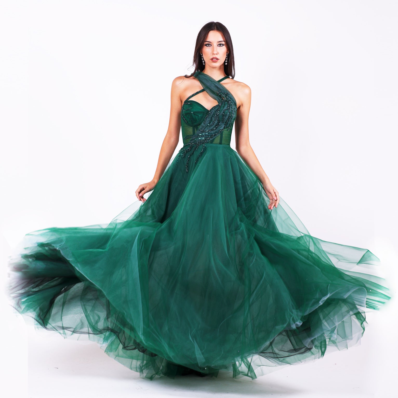 Дълга абитуриентска рокля Grevillea LIZA KAIN София. Официална рокля от тъмнозелен тюл. Корсет с полупрозрачна основа със сърцевидно деколте и апликация от тюлена драперия с дантела в кръстоска с тънка презрамка. Обемна тюлена пола от различни слоеве. 