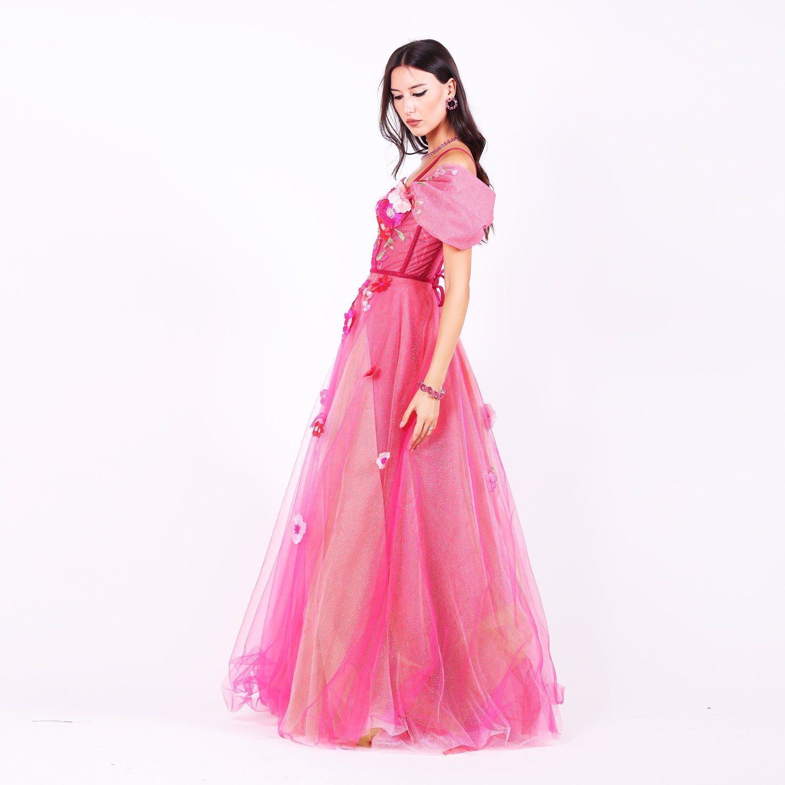 Дълга абитуриентска рокля Forsythia LIZA KAIN София. Официална розова рокля от тюл. Корсет със сърцевидно деколте с тънки презрамки и обемни паднали ръкави с апликации от дантела от памучни цветя. Прозрачна основа и връзки на гърба. Клоширана тюлена пола, покрита с разноцветни памучни цветя. 