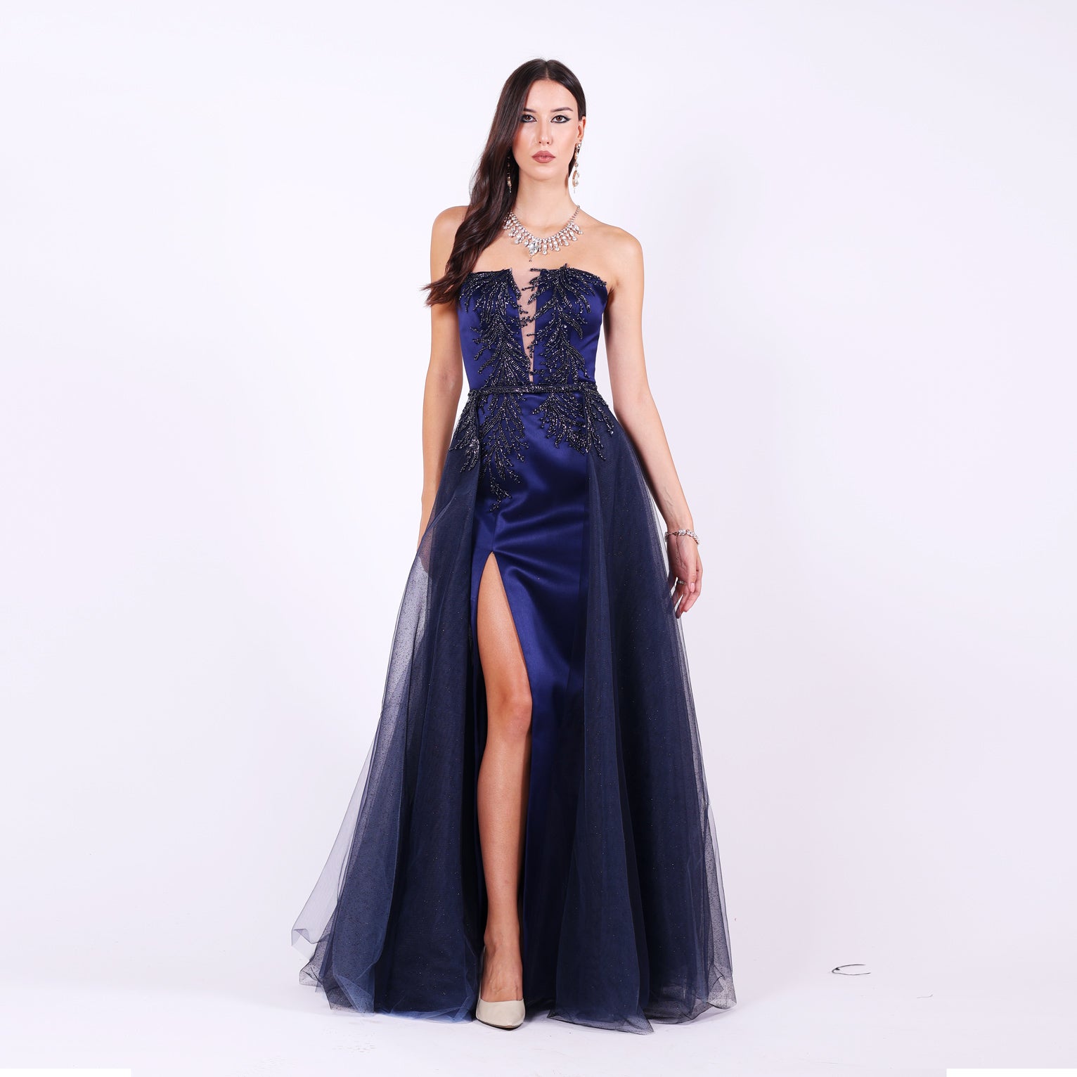 Дълга абитуриентска рокля Mathiola LIZA KAIN София. Официална рокля от тъмносин сатен. Корсет с равно деколте и мрежа, покрит с графитена дантела от камъчета и мъниста. Апликации от дантела по талията и полата. Пола тип русалка с цепка и шлейф. Обемна тюлена пола с колан.