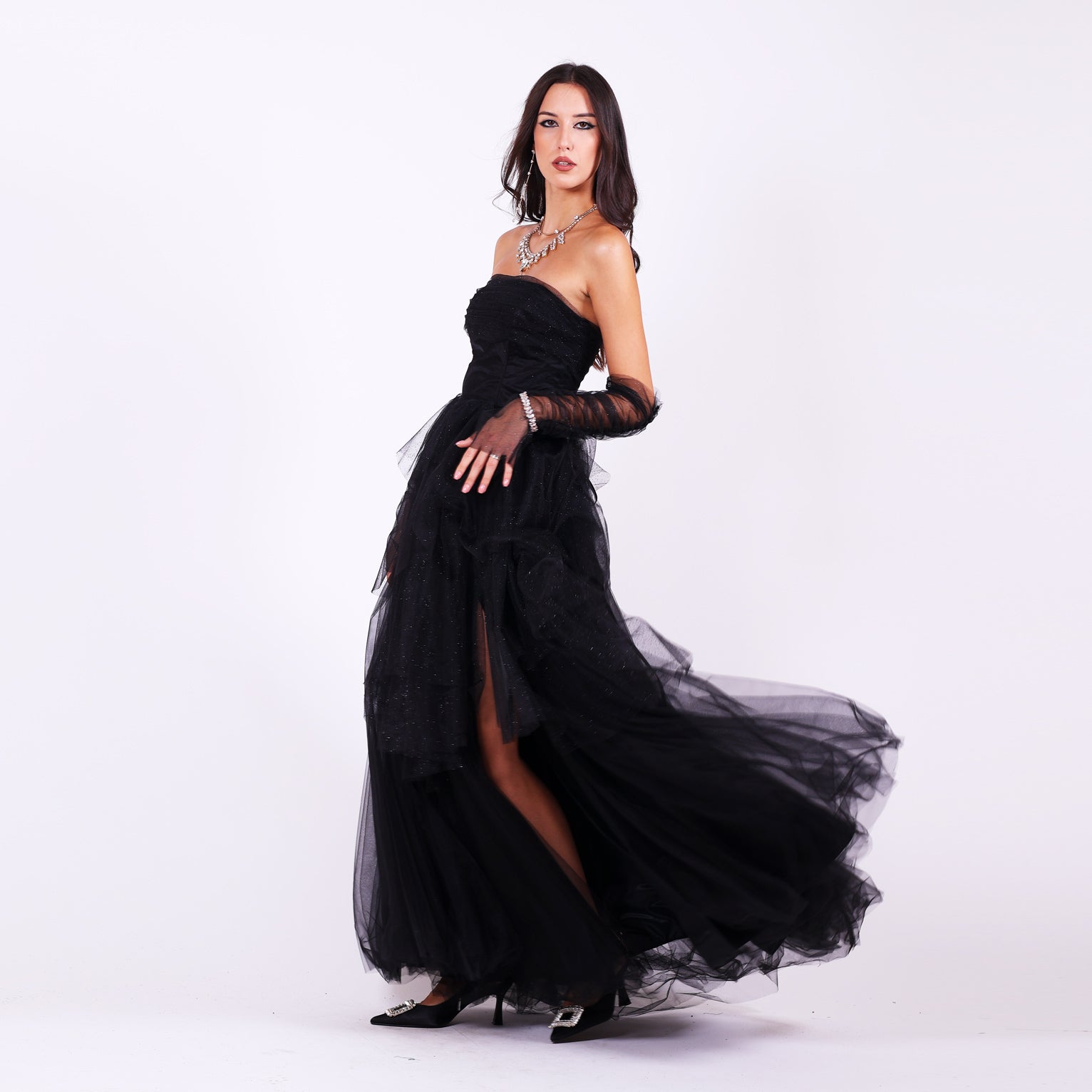 Дълга абитуриентска рокля Gloxinia LIZA KAIN София. Официална рокля от черен тюл. Корсет с равно деколте с лека драперия. Обемна пола от блестящ тюл с цепка. Тюлени ръкавици без пръсти.