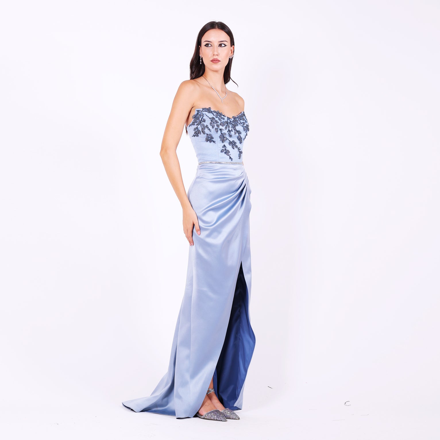 Дълга абитуриентска рокля Lunaria LIZA KAIN София. Официална сатенена рокля със силует русалка. Корсет със сърцевидно деколте с изострени ъгли и апликации от синя флорална дантела. Пола тип русалка с цепка с плохи и прехлупване.