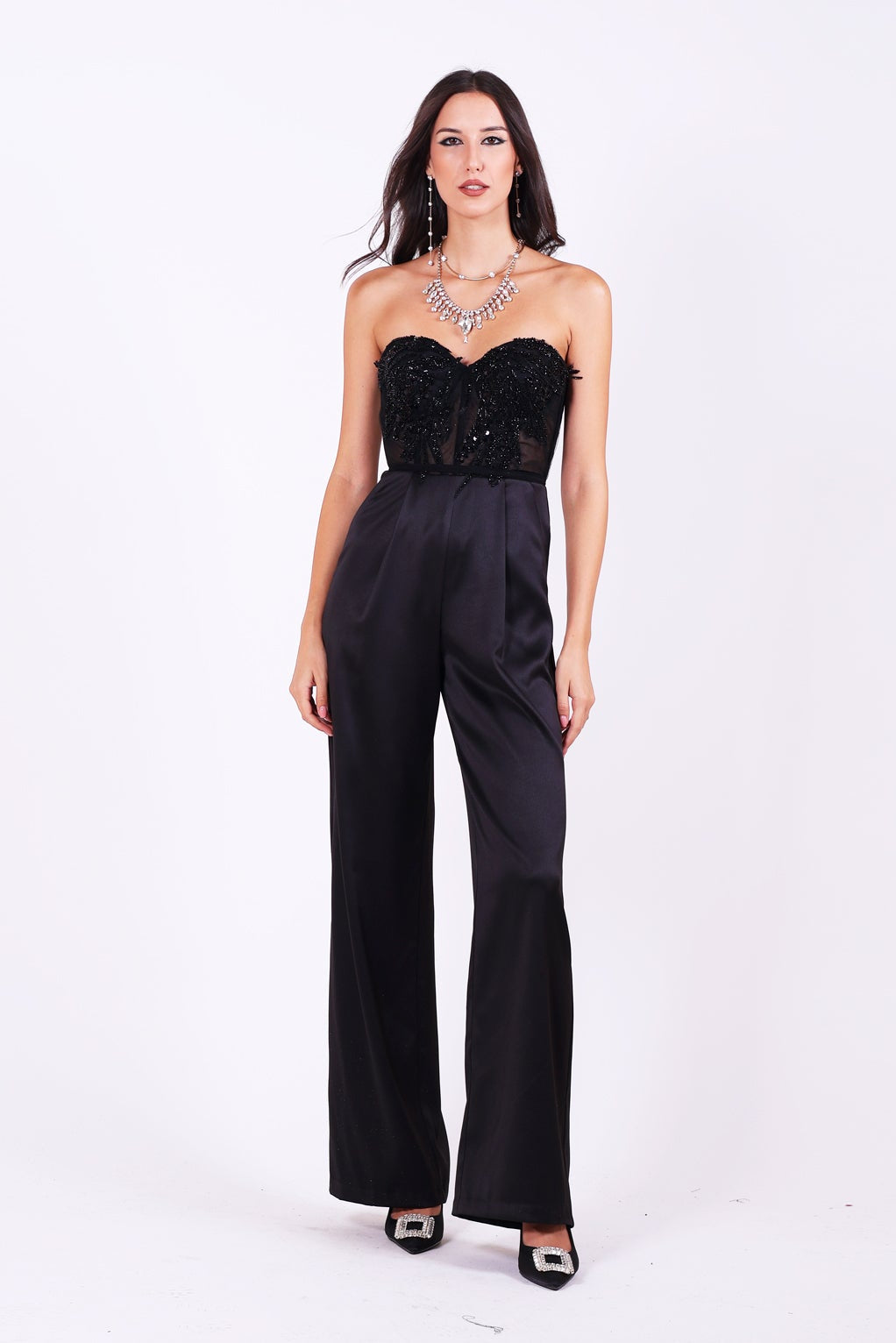 Официален гащеризон Carlina LIZA KAIN София. Черен сатенен гащеризон. Корсет без презрамки със сърчевидно деколте с полупрозрачна основа, покрита с блестяща черна дантела от мъниста и камъни. Широк сатенен панталон с плохи.