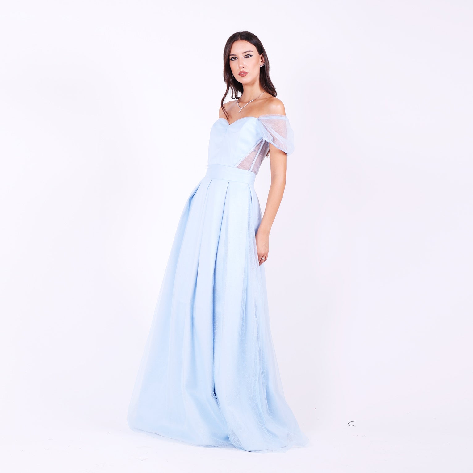 Дълга абитуриентска рокля Alcea LIZA KAIN София. Официална рокля от бебешкосин тюл. Корсет със сърцевидно деколте и паднали ръкави. Полупрозрачни панели от двете страни на талията. Обемна пола.