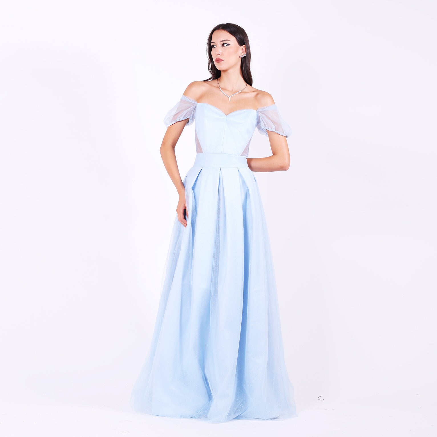 Дълга абитуриентска рокля Alcea LIZA KAIN София. Официална рокля от бебешкосин тюл и сатен. Корсет с форма на сърце с полупрозрачни панели от двете страни и паднали ръкави. Клоширана пола с широк колан и плохи.