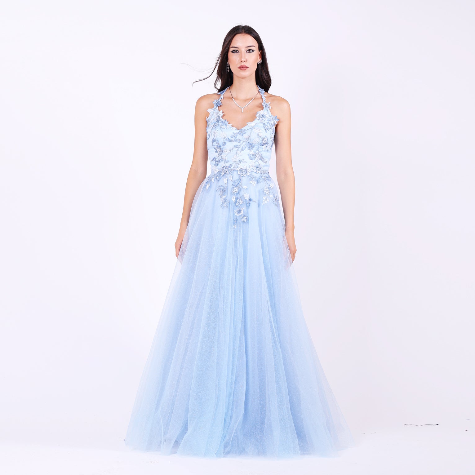 Дълга абитуриентска рокля Parrotia LIZA KAIN София. Официална рокля от светлосин тюл. Корсет с V-образно деколте с презрамки, покрит с флорална памучна дантела. Разкроена тюлена пола с флорални апликации по талията.