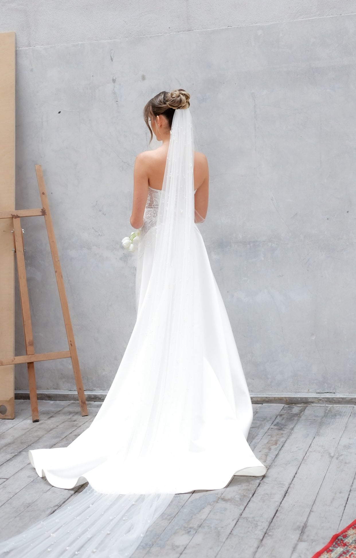 Официална булчинска рокля Emeralda Boheme LIZA KAIN Bridal с артистичен асиметричен силует, корсет с връзки и дълга бяла сатенена пола.