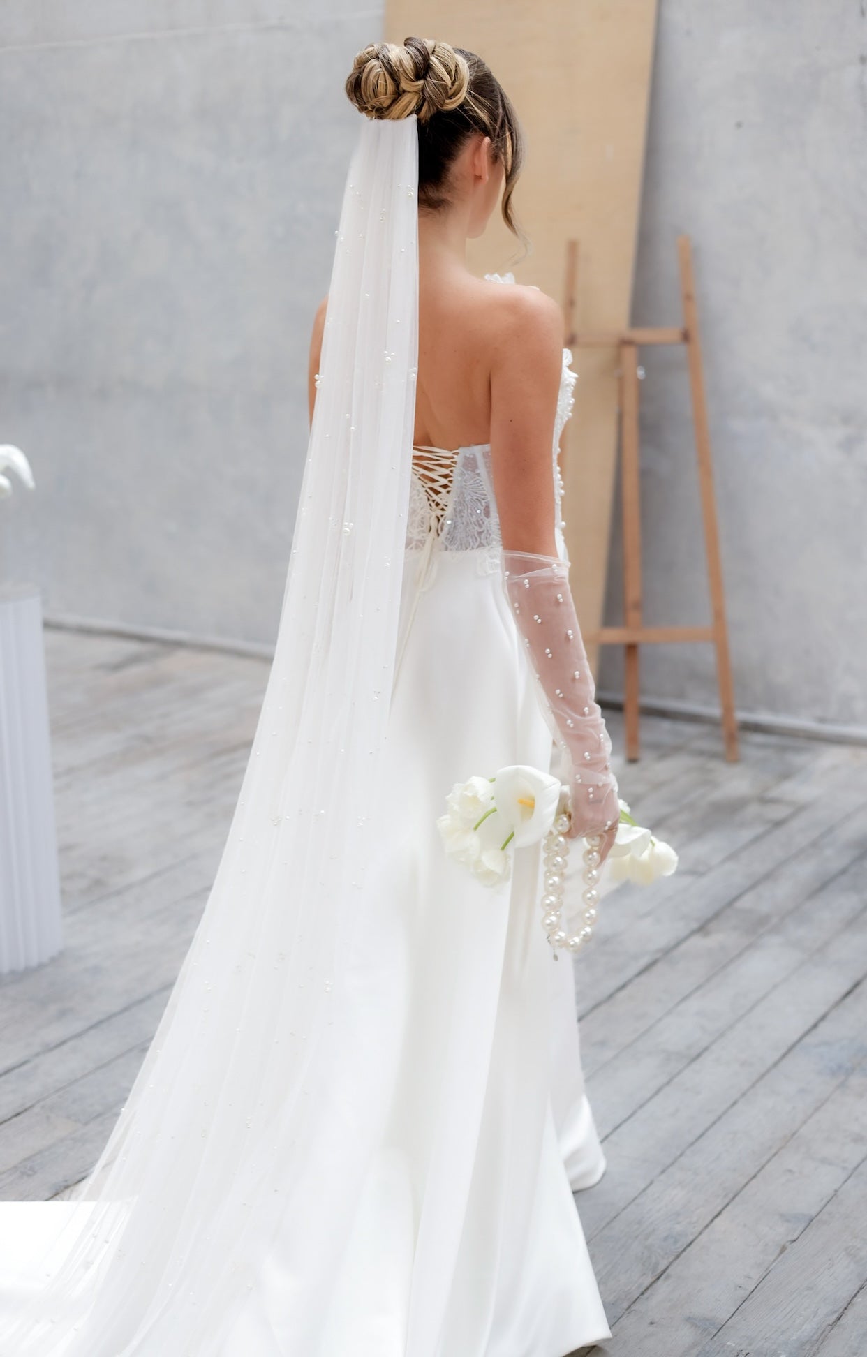 Елегантна булчинска рокля Emeralda Boheme LIZA KAIN с корсет декориран от флорална дантела и перли, закопчване с връзки на гърба и сатенена А-линия пола.