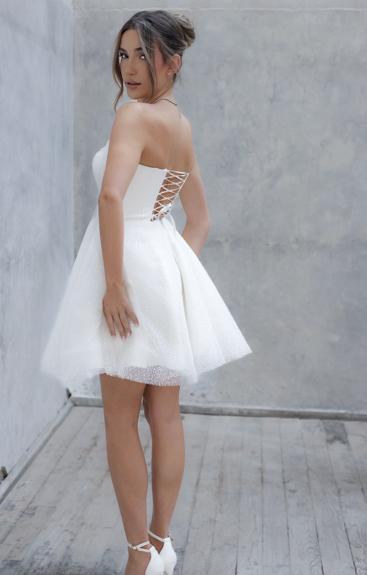 Елегантна къса булчинска рокля Elegant Mini LIZA KAIN София с изчистен корсет с връзки, колан в талията и обемна тюлена пола с фин блясък.