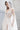 Сватбена рокля Cordelia Grace от LIZA KAIN bridal с многопластова тюлена пола с висока цепка. Дизайнът завършва с фин, ефирен шлейф, който придава лекота при движение. Визията съчетава луксозна текстура и благородно присъствие.