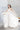 Елегантна булчинска рокля с изчистен силует от LIZA KAIN bridal. Моделът се отличава с корсет с фина драперия и изящна дълга пола с мек блясък. Визията е допълнена от дълги дантелени ръкавици с флорални мотиви.