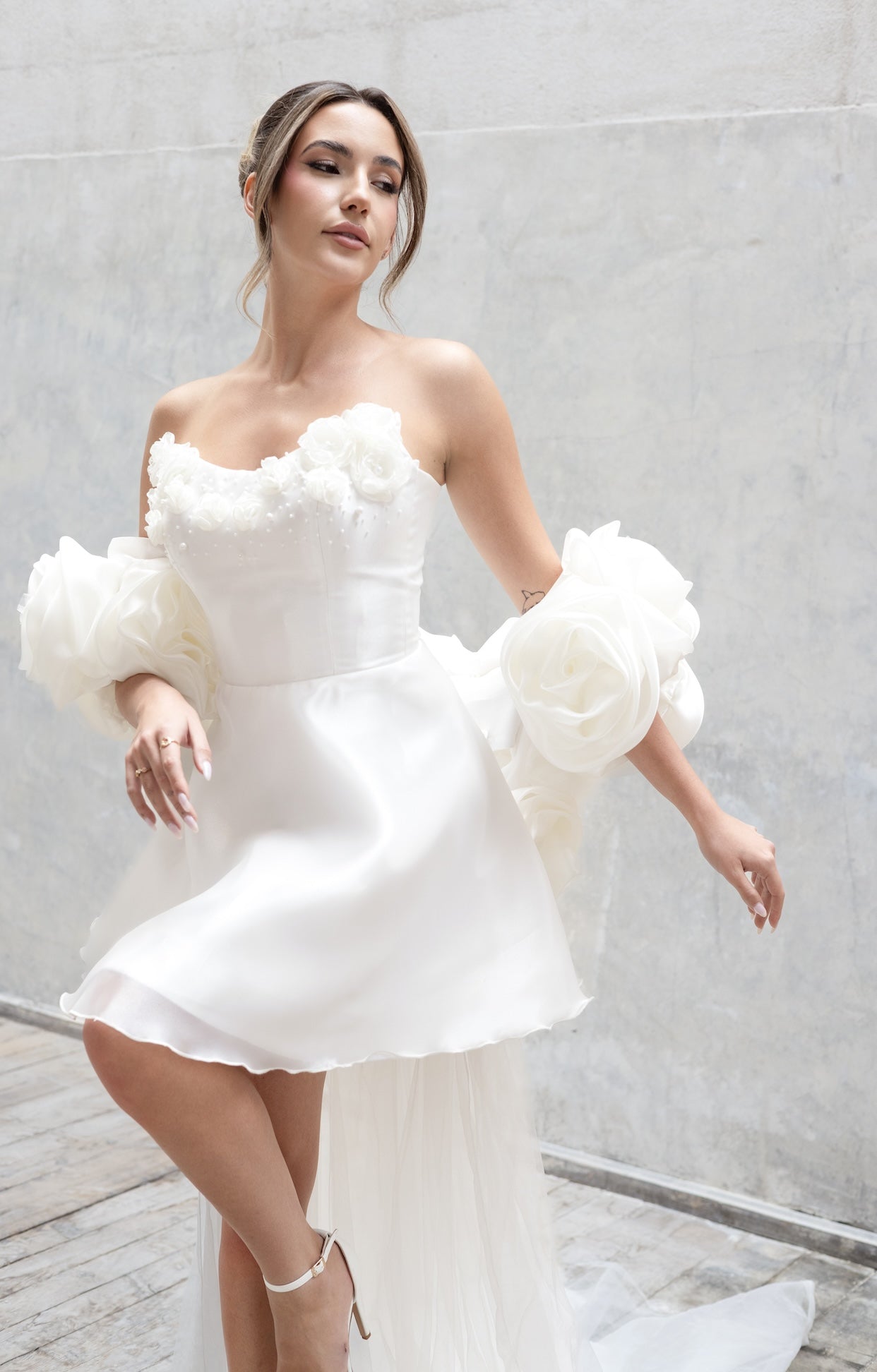 Официална къса булчинска рокля Helen LIZA KAIN Bridal от фина бяла органза, с корсетирана горна част и детайл от триизмерни флорални елементи с камъчета и перлички, и къса обемна пола.