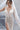 Дълга булчинска рокля Andromeda Starfall от LIZA KAIN bridal със сияйно присъствие и втален силует, който следва линията на тялото. Моделът съчетава прозрачна основа с богата орнаментална декорация и висока странична цепка.