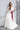 Класическа и ефектна булчинска рокля Nerissa от LIZA KAIN bridal в принцески стил с обемна пола от многослоен тюл. Моделът съчетава равно деколте с драперии и нежен блясък, допълнен от ефирни ръкавици.