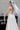 Официална булчинска рокля Moonblush LIZA KAIN Bridal с корсетирана горна част, полупрозрачна талия с нашита дантела, закопчаване с връзки. Пола от бяла органза с флорални елементи.