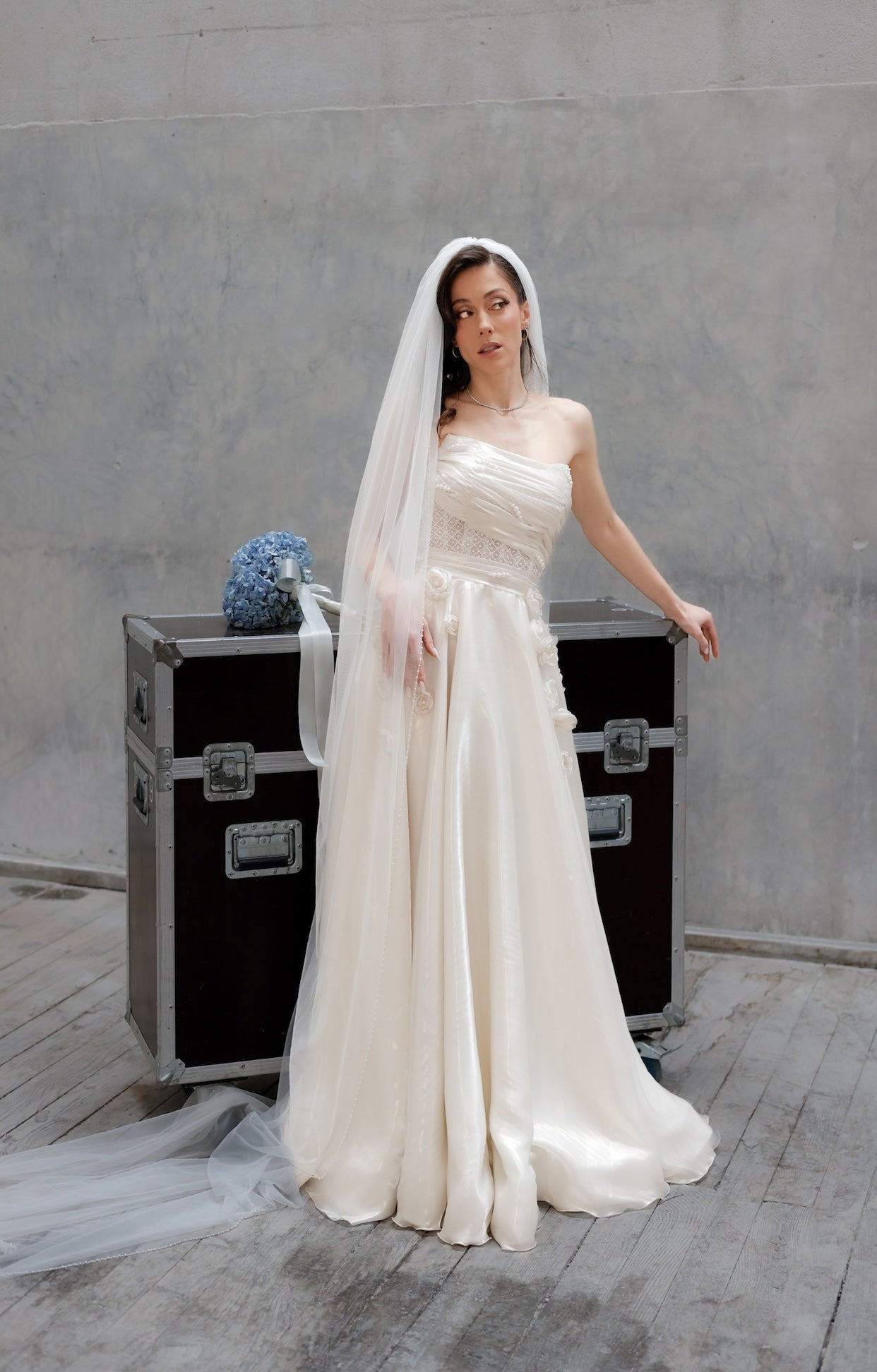 Елегантна булчинска рокля Moonblush LIZA KAIN Bridal от бяла органза с драпиран корсет, ръчно нашита дантела с перли и декорация от флорални елементи. Права пола с ръчно изработени апликации.