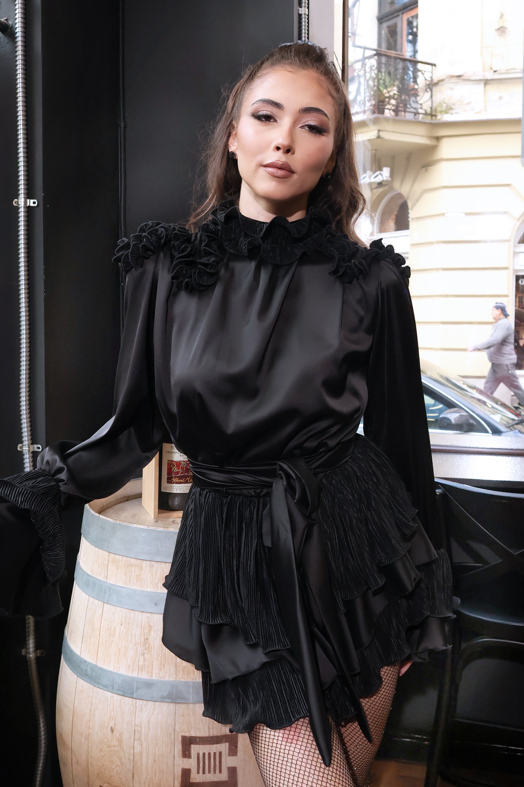 Къса официална мини рокля Dark Romance LIZA KAIN София. Черна сатенена рокля с висока яка с къдрици. Дълъг ръкав тип камбана. Сатенен колан. Разкроена пола.