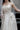 Детайл от талията на булчинската рокля Moonblush от LIZA KAIN bridal, подчертана с фина дантелена лента. Ръчно нашитите нежни перли добавят изискан блясък и изтънченост към силуета.