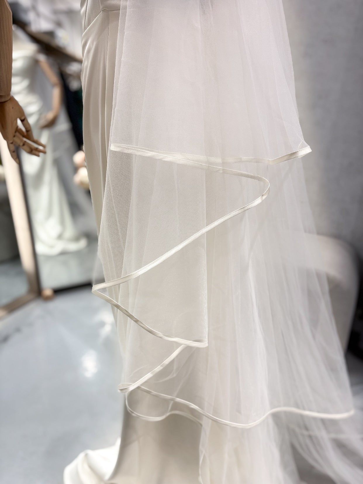 Aurora Silk -тюлен бял воал с елегантен сатенен кант, който прави всяка рокля още по-зашеметяваща. 