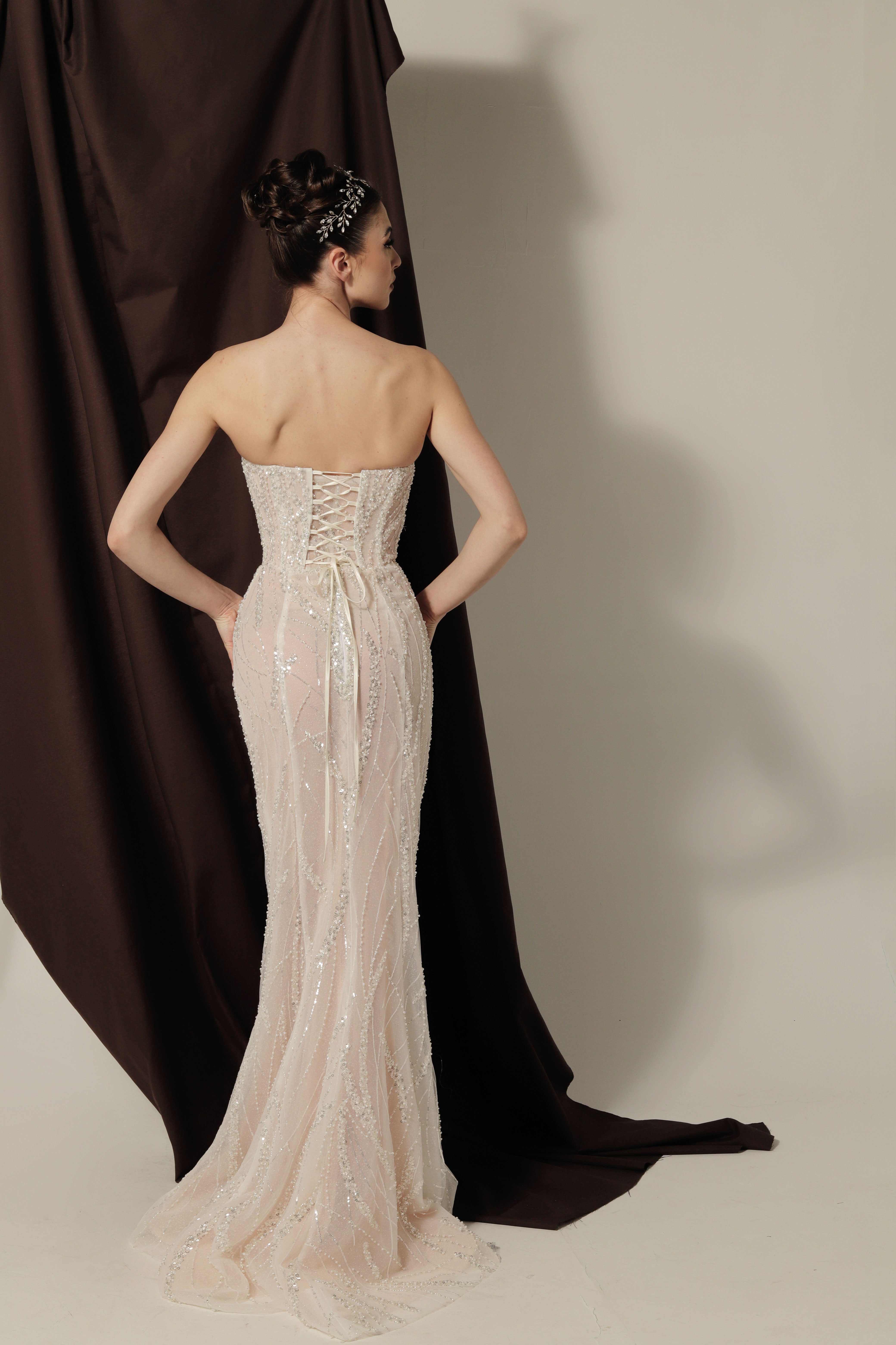 Дълга булчинска рокля русалка Rubelle LIZA KAIN София. Бяла официална рокля с телесна основа, покрита с дантела от мъниста и перли. Изострен корсет с V-образно деколте с мрежа. Пола по тялото тип русалка.