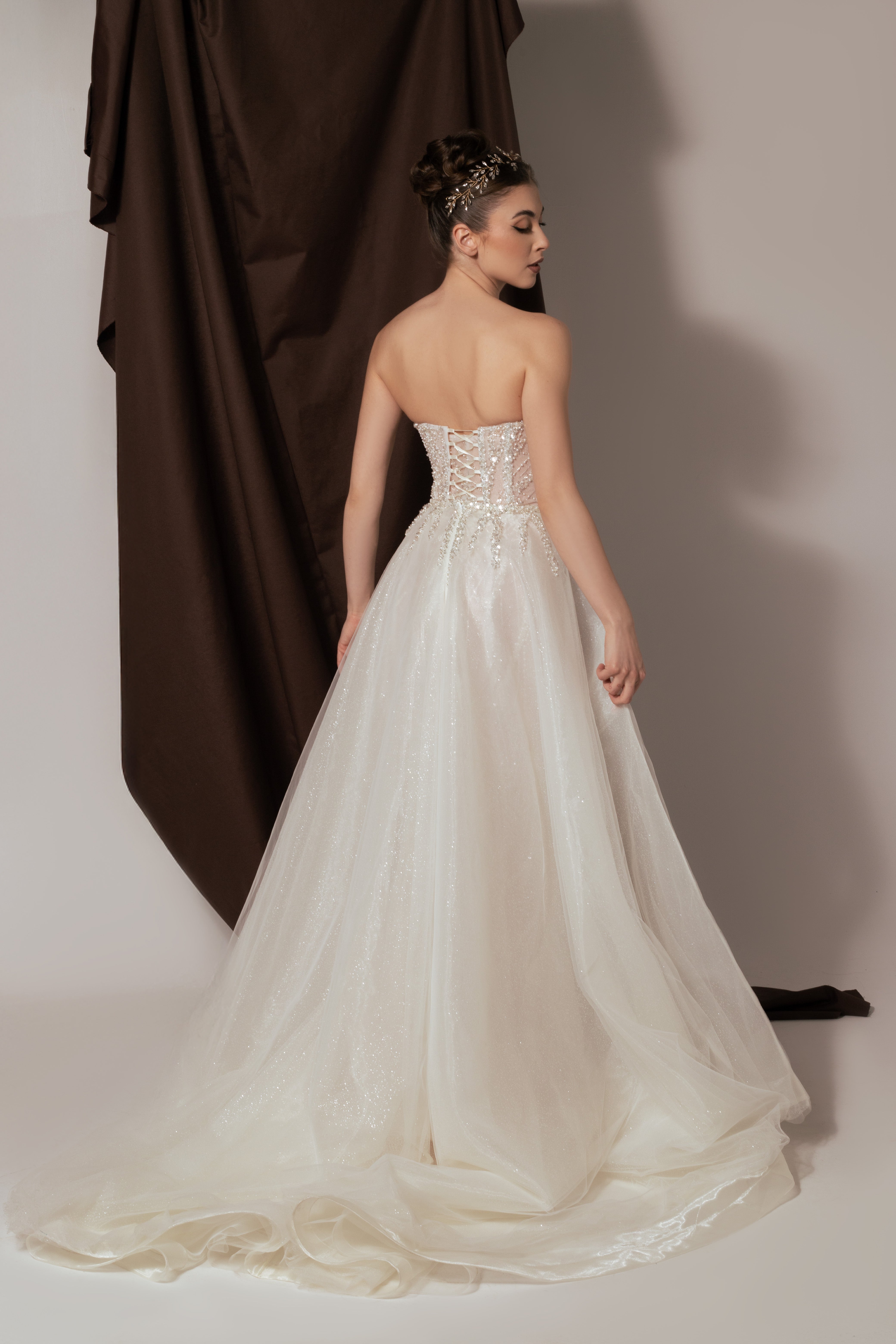 Дълга булчинска рокля русалка Rubelle Grande LIZA KAIN София. Бяла официална рокля с телесна основа, покрита с дантела от мъниста и перли. Изострен корсет с V-образно деколте с мрежа и връзки на гърба. Бухнала тюлена пола.