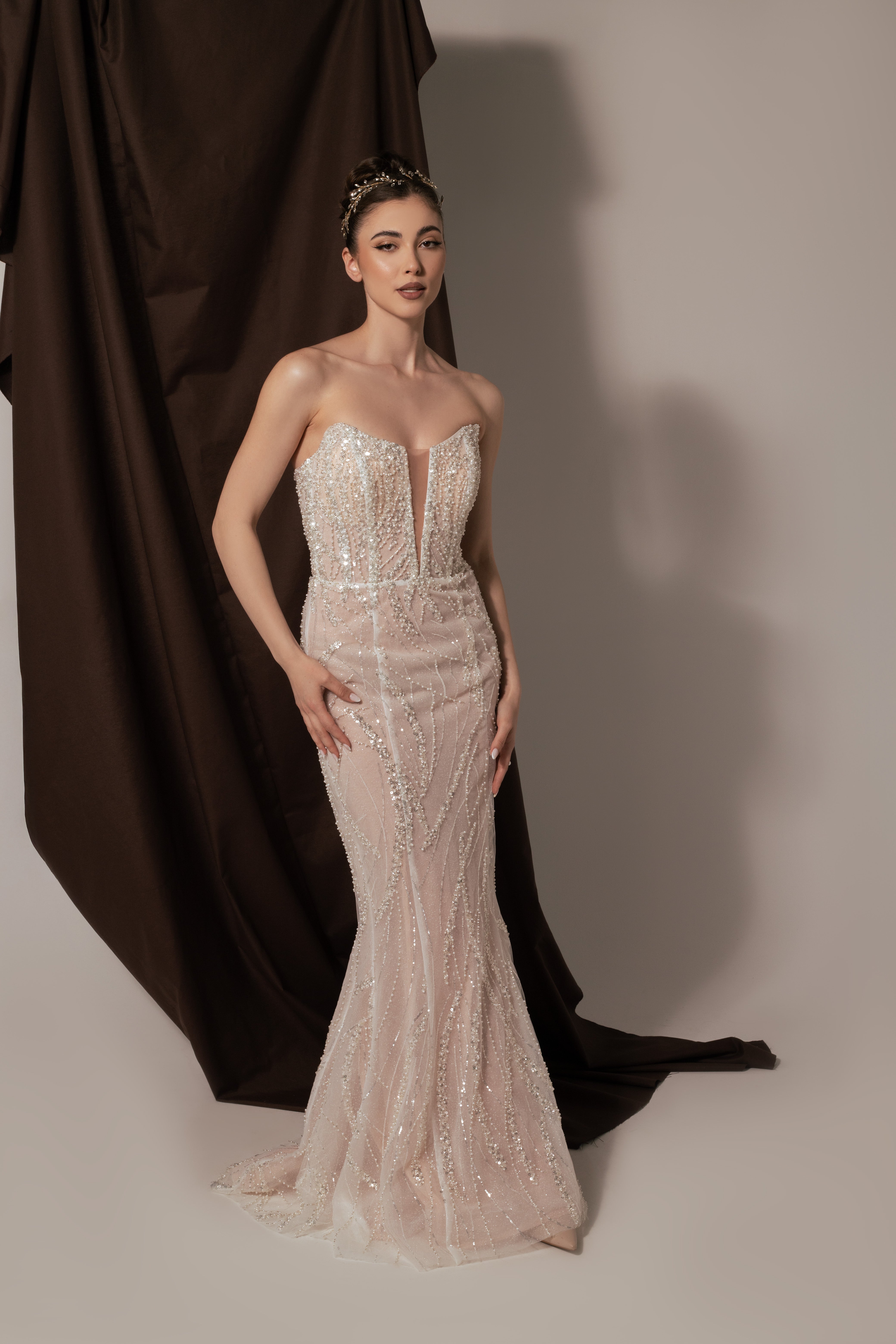 Дълга булчинска рокля русалка Rubelle LIZA KAIN София. Бяла официална рокля с телесна основа, покрита с дантела от мъниста и перли. Изострен корсет с V-образно деколте с мрежа. Пола по тялото тип русалка.