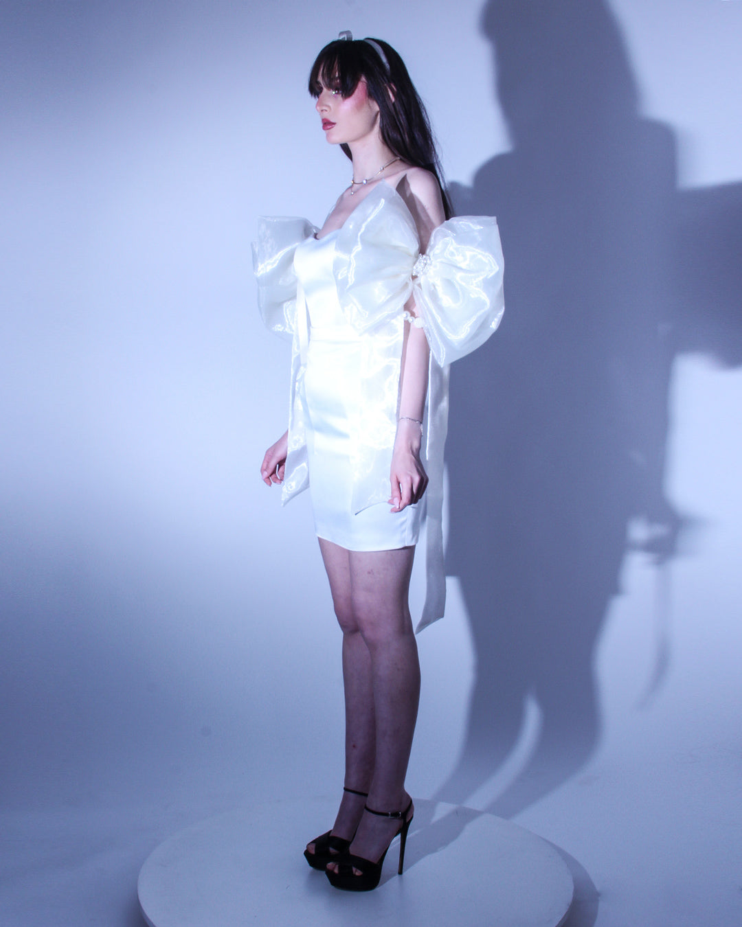 Къса рокля Lucinda LIZA KAIN София. Официална мини рокля от бяла органза. Корсет със сърцевидно деколте и паднали ръкави от големи панделки от органза. Права пола. Алтернатива за булчинска рокля.