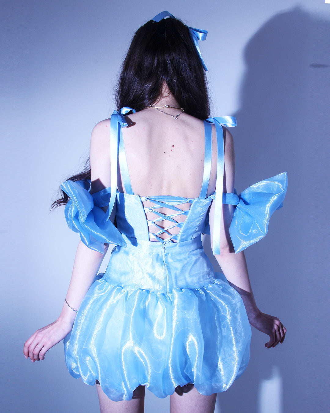 Къса рокля Mirabel LIZA KAIN София. Официална рокля от синя органза. Корсет със сърцевидно деколте и презрамки тип панделка. Паднали ръкави от големи панделки от органза. Връзки на гърба. Пола тип балон. 