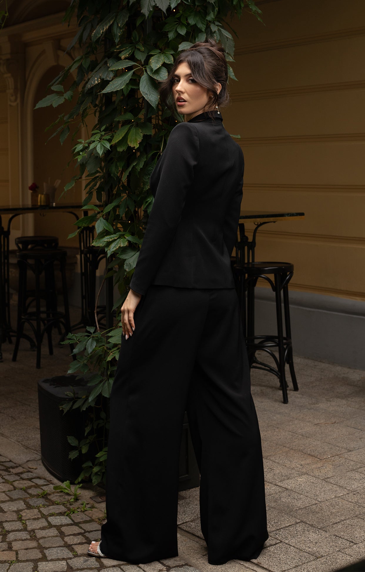 Дълго официално сако Noire LIZA KAIN София. Класическо черно сако с дълбоко деколте с подлънки на раменете. Джобове с капаци. Официален панталон Noire със свободна кройка.