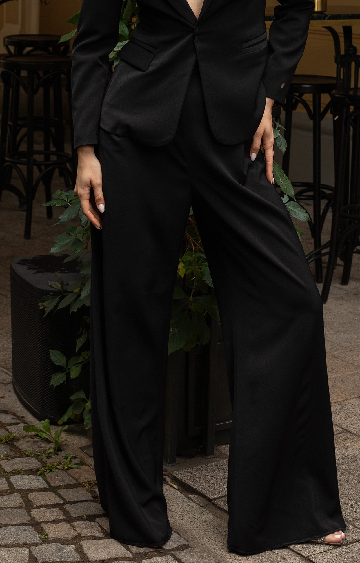 Дълго официално сако Noire LIZA KAIN София. Класическо черно сако с дълбоко деколте с подлънки на раменете. Джобове с капаци. Официален панталон Noire със свободна кройка.