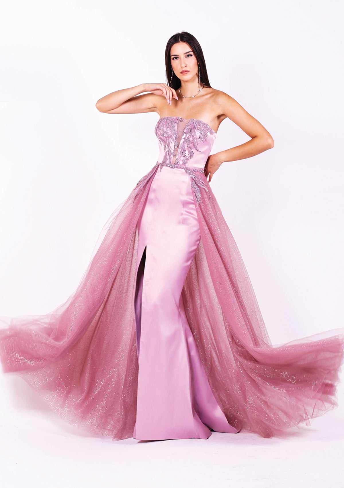 Дълга абитуриентска Rhodonite LIZA KAIN София. Официална рокля от сатен в цвят пепел от рози. Корсет с равно деколте с мрежа и апликации от светлолилава дантела от мъниста. Права пола с цепка. Бухнала тюлена пола с колан с дантела.