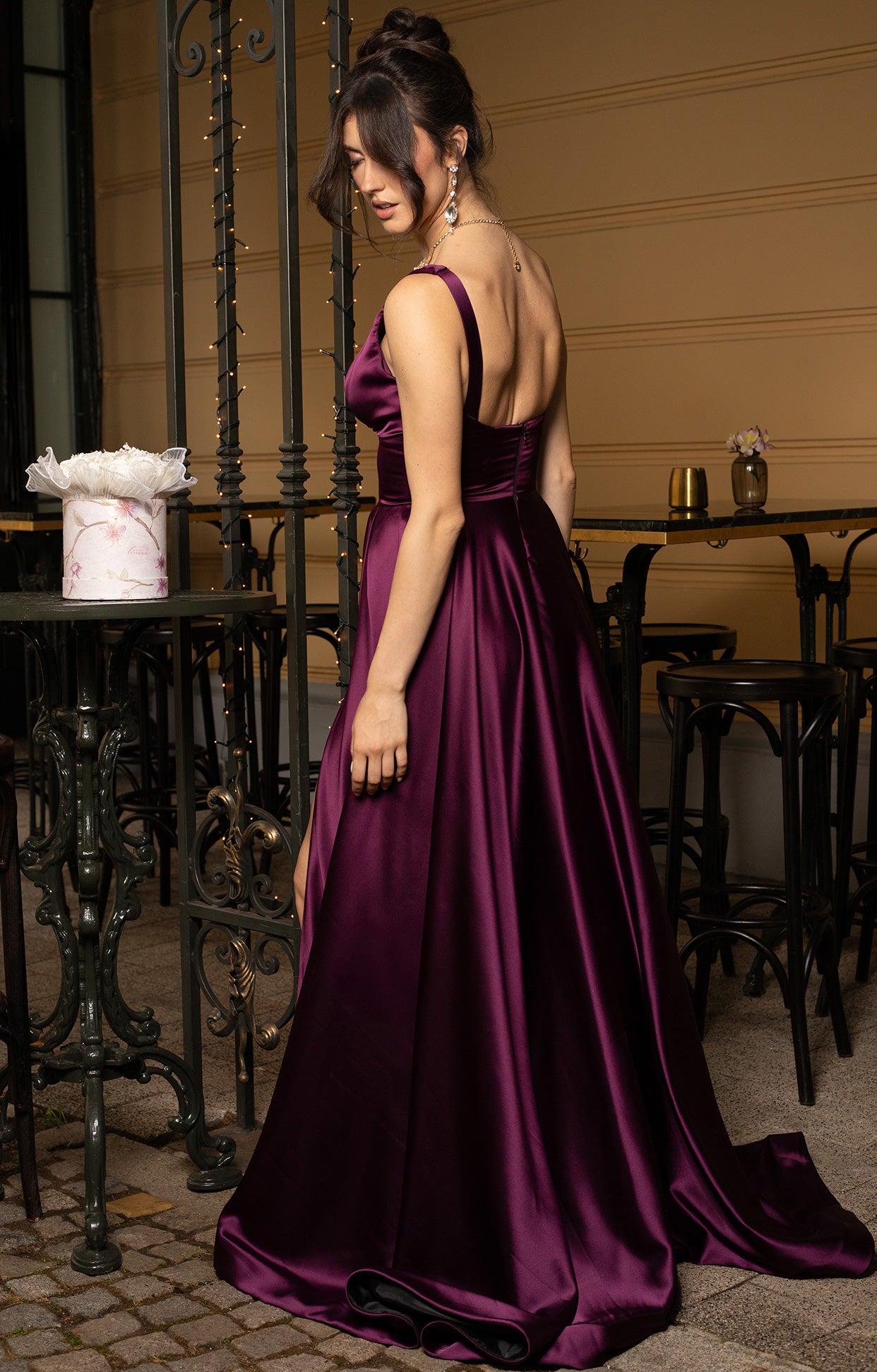 Официална дълга абитуриентска рокля Velra LIZA KAIN София. Сатенена рокля в дълбоко виолетово. V-образно деколте с презрамки и лека драперия. Широк колан. Полугол гръб със скрит цип. Разкроена пола.