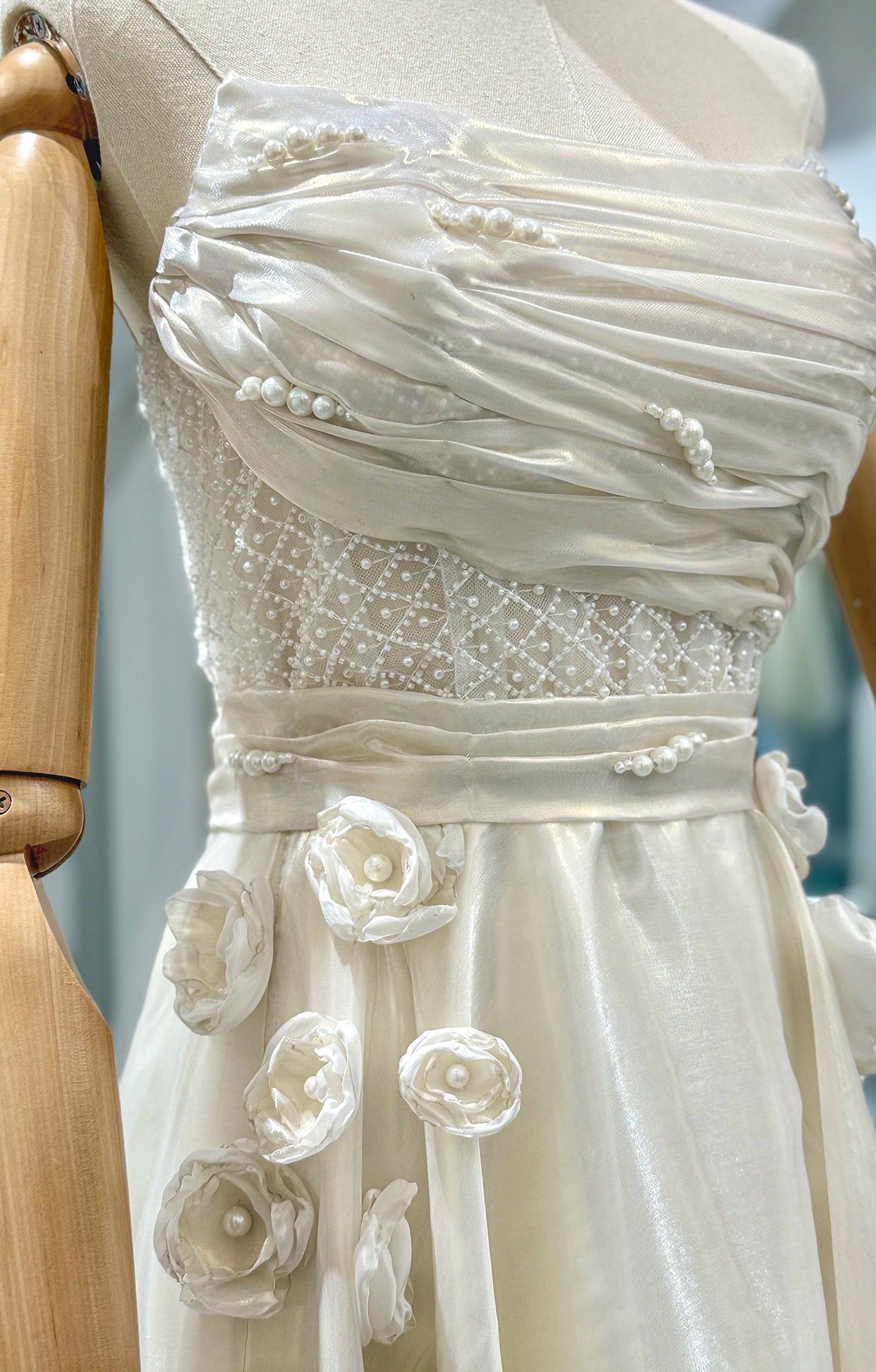 Дълга булчинска рокля Moonblush LIZA KAIN София. Официална бяла рокля от органза. Корсет с остри ъгли и драперия с перли. Основа от геометрична дантела. Колан и пола от органза с апликации от цветя и перли.